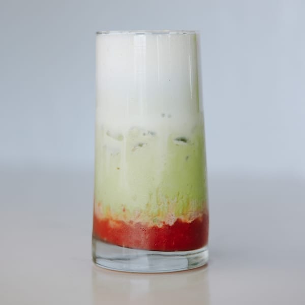 A tall glass of layered drink with red, green, and white sections, likely a Braxton's Kitchen smoothie.
