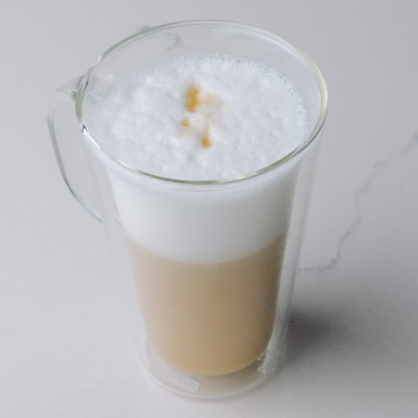 Braxton's Kitchen latte in a clear mug with frothy milk and a drizzle of caramel.