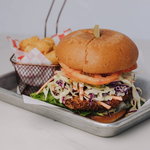 Braxton's Kitchen fried chicken sandwich with coleslaw, tomato, and lettuce, served with tater tots.